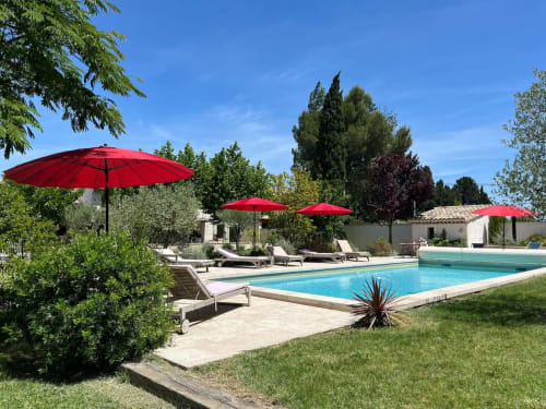 Luxury Provence pool villa with turquoise swimming pool, red umbrellas, loungers, and traditional stone buildings at Mas St