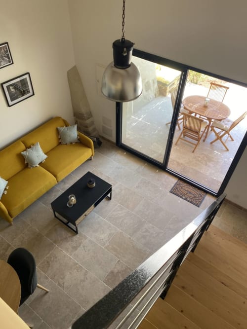 Modern living room at Mas St André cottage in Provence with yellow sofa, black pendant lamp, and patio access to outdoor