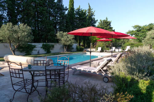 Provence cottage pool area with red umbrellas, lounge chairs, and dining setup at Mas St André