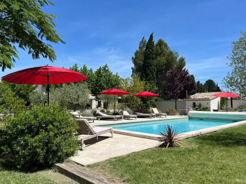 Luxury Provençal villa pool with red umbrellas, loungers, and manicured gardens at Mas St André, Saint-Andiol