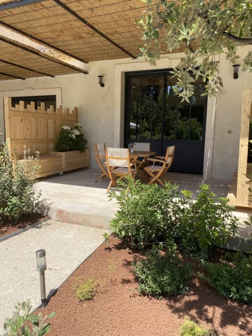 Provence cottage patio with wooden pergola, dining chairs, black doors, and Mediterranean garden at Mas St André