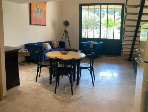 Modern cottage living room with blue sofa, round dining table, black chairs, and garden views at Mas St André Provence B&B