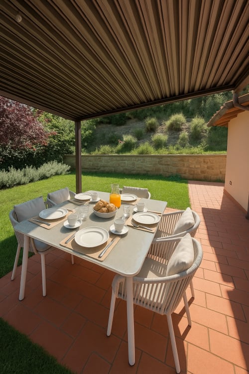 Colazione all'aperto nella veranda coperta di Cognaia Loft ad Arezzo, con tavolo, sedie e vista sul giardino verde