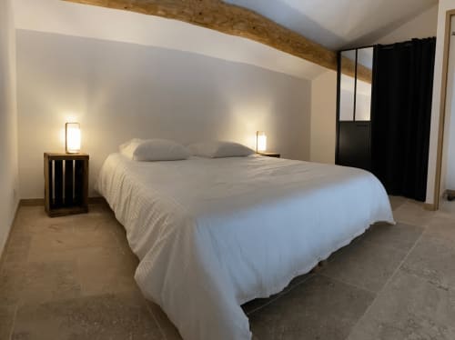Modern bedroom in Provence cottage with queen bed, white bedding, wooden beam ceiling, and bedside lamps.