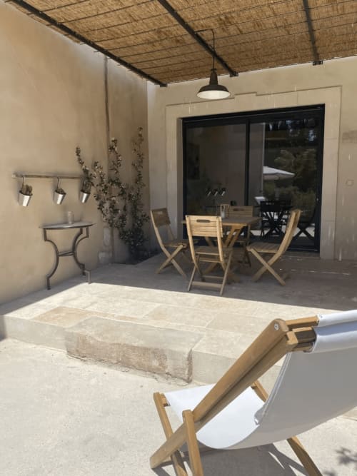 Outdoor terrace at Provence cottage with dining area, lounger, stone pool, wisteria, and black sliding doors