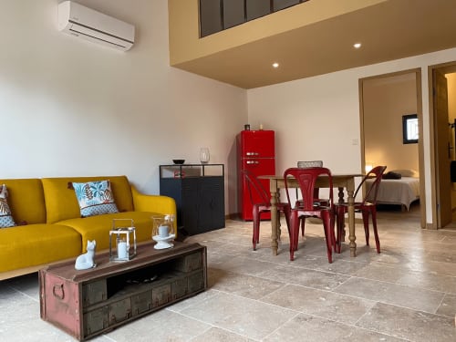 Intérieur lumineux de cottage avec canapé jaune, chaises rouges, table à manger et réfrigérateur rouge au Mas St André en Provence