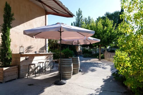 Provence cottage outdoor patio with umbrella, wooden bar counter, wine barrels, and lush greenery at Mas St André