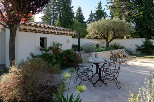 Provence cottage terrace with dining table, garden seating, and rustic white stone building at Mas St André