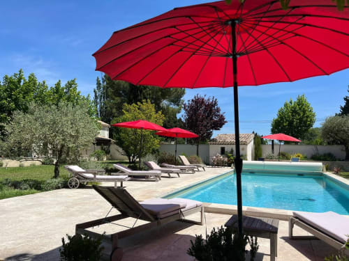 Red umbrellas and loungers by crystal pool at Mas St André cottage in Provence, France