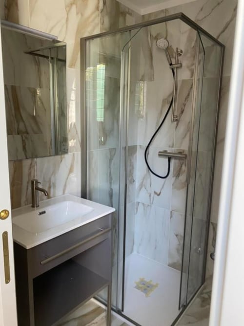 Modern bathroom at Casanova Hideaway Venice with glass shower enclosure, marble tiles, and vanity sink