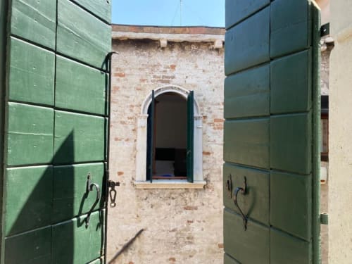 Porte in legno verde incorniciano un'arcata in una corte storica veneziana presso il Rifugio Casanova