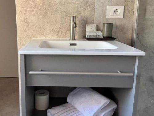 Moderno lavabo di lusso a Casanova Hideaway Venezia con lavandino bianco, rubinetto in metallo e scaffali con asciugamani
