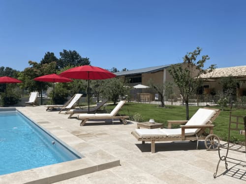 Zone piscine du Mas St André avec transats, parasols rouges et vue sur la campagne à Saint-Andiol