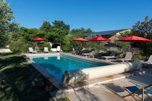 Piscine du Mas St André avec parasols rouges, transats et vue sur la campagne à Saint-Andiol