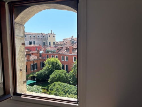 Arched window view of Venice rooftops and red buildings from Casanova Hideaway hotel room