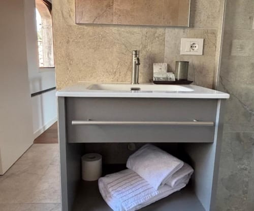 Modern bathroom vanity at Casanova Hideaway Venice with tile backsplash, white sink, and storage shelves with towels