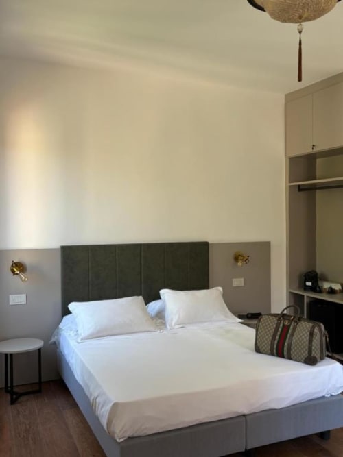 Modern bedroom at Casanova Hideaway Venice with white bedding, dark headboard, and city view