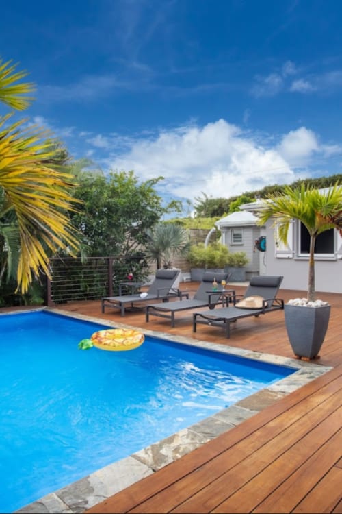 Piscine Paradise Location avec chaises longues, palmiers et petits cottages blancs à Fort-de-France, Martinique