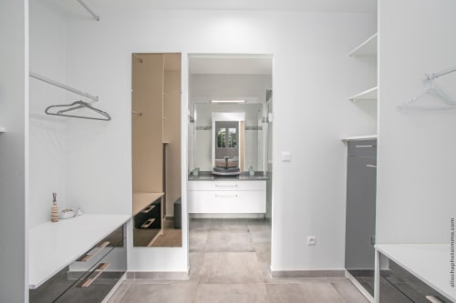 Modern walk-in closet and dressing room in Paradise Location villa with mirrored door, white cabinetry, and ensuite bathroom