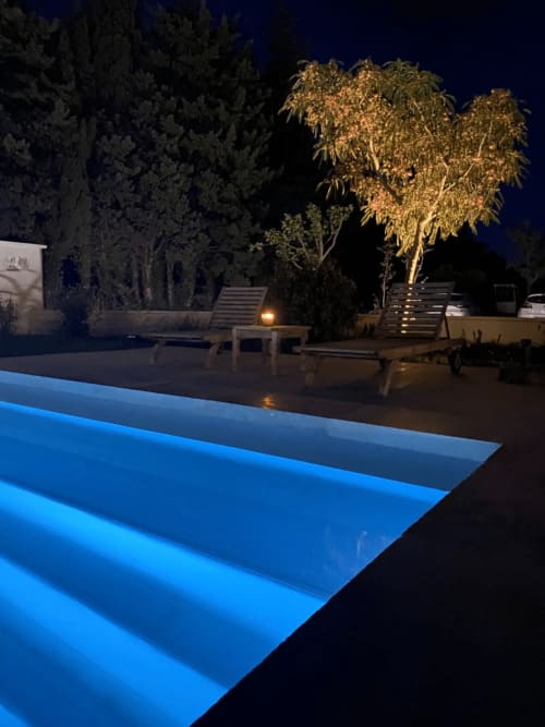 Mas St André pool at night with blue LED lighting, lounge chairs, and illuminated trees in Saint-Andiol