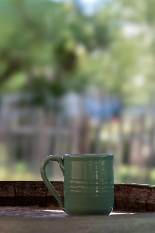 Green ceramic mug on wooden railing at Mas St André, a French bed and breakfast in Saint-Andiol