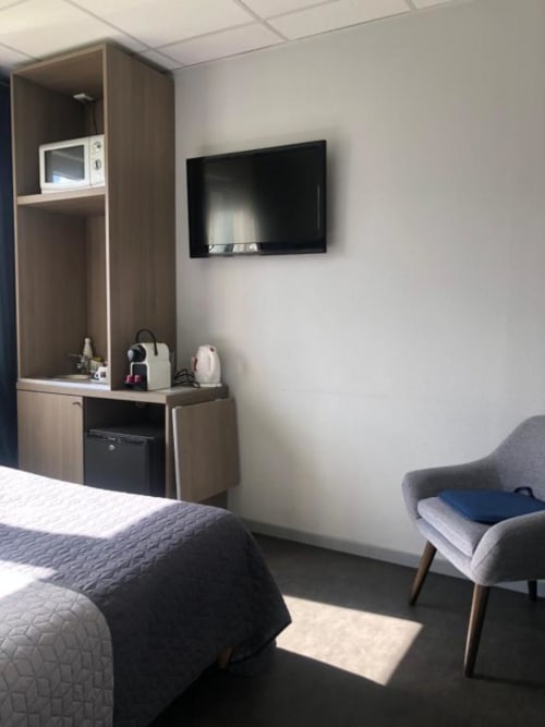 Chambre double moderne à l'hôtel Cosyade à Bourbourg, équipée d'un lit, TV murale, cafetière et coins salon confortables