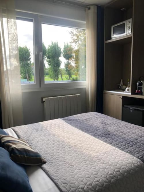 Economy double room at Cosyade hotel in Bourbourg with bed, window view, radiator, and dark vanity desk with microwave