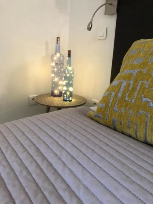 Cozy bedside table with illuminated wine bottle lights at Cosyade Family Studio in Bourbourg