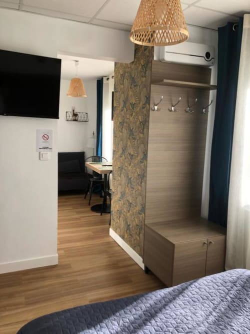 Studio supérieur moderne à l'hôtel Cosyade à Bourbourg avec kitchenette, coin repas et entrée avec patères et tissu tressé