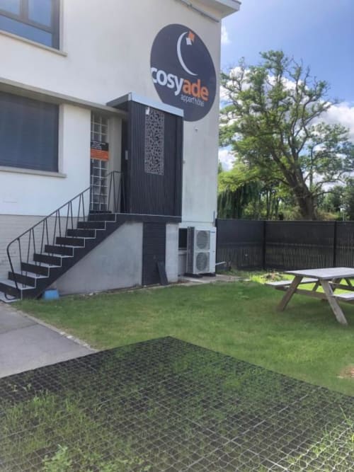 Cosyade hotel exterior in Bourbourg with entrance stairs, lawn, picnic table, and moon logo signage