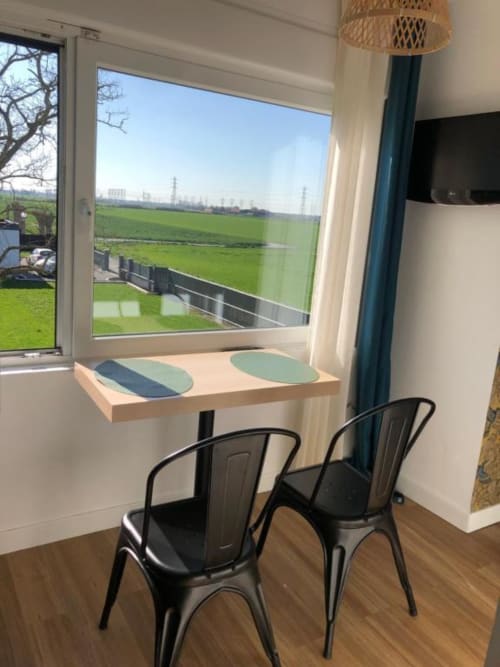 Studio Supérieur Cosyade, coin repas avec vue sur le jardin par grande fenêtre, chaises noires, table en bois, hôtel Bourbourg