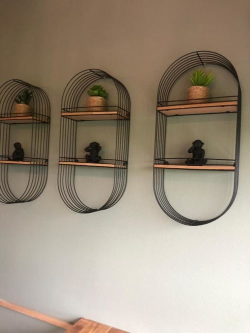 Three wall-mounted wire shelving units with wooden shelves, potted plants and black decorative objects at Cosyade hotel in
