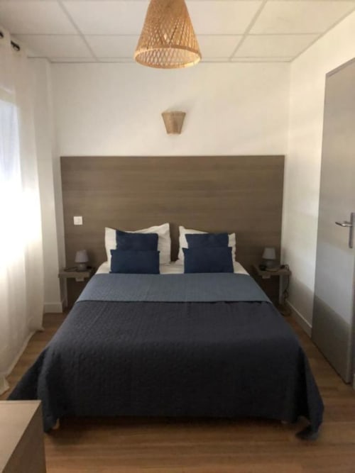 Superior Studio bedroom at Cosyade hotel in Bourbourg with dark bedding, woven pendant light, and modern amenities