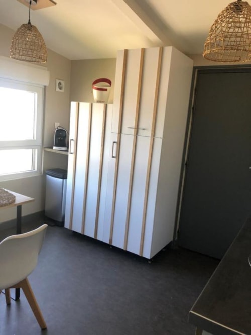 Cosyade Family Studio kitchen with white cabinetry, dining area, and woven pendant lights in Bourbourg