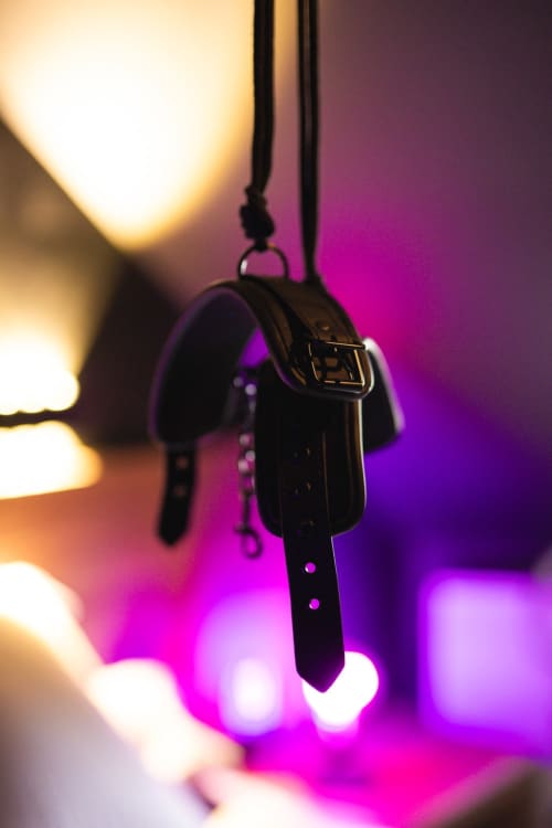 Black key hanging from cord against vibrant magenta and golden lighting in romantic apartment