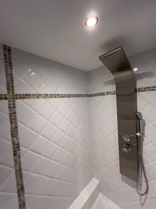 Modern shower enclosure with rainfall showerhead, brass fixtures, and white subway tile in romantic Vannes apartment