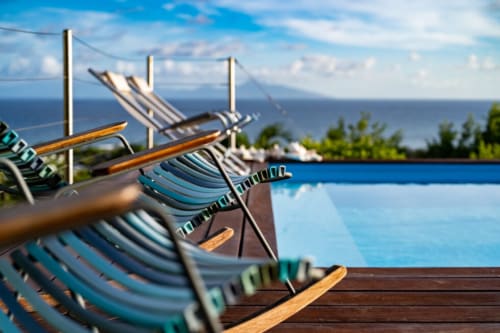 Chaises longues au bord de la piscine à débordement surplombant l'océan à Chez Marie et Philippe, Marie-Galante