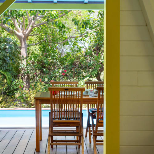 Table et chaises en bois sur une terrasse dominant un jardin verdoyant chez Marie et Philippe, Marie-Galante