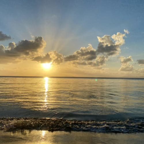 Coucher de soleil sur la mer des Caraïbes à Chez Marie et Philippe, Marie-Galante, Guadeloupe avec nuages dorés et vagues de plage