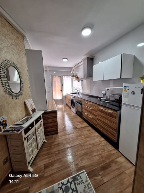 Modern kitchen in Benavente vacation rental with wood cabinets, white appliances, and tiled flooring
