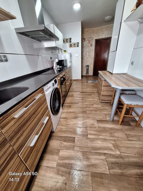 Modern kitchen in tourist apartment in Benavente with striped wood cabinets, white appliances, and dining table