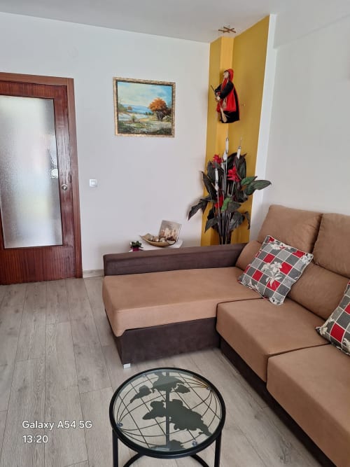 Cozy living room in Benavente tourist apartment with tan sofa, decorative yellow wall accent, and globe table