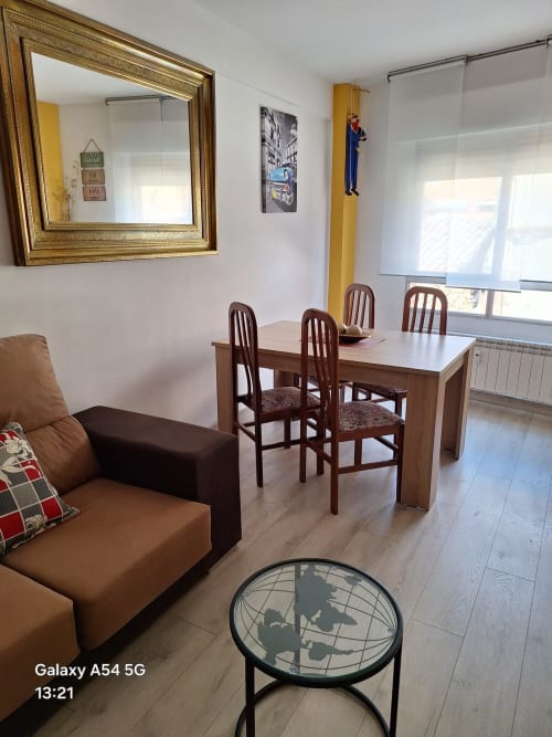 Modern living room in Benavente tourist apartment with wooden dining table, brown leather sofa, and globe coffee table