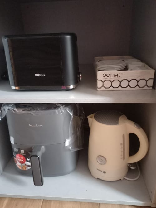 Kitchen appliances on white shelves: Koenic toaster, Octime dispenser, Moulinex air fryer, and cream kettle in Benavente
