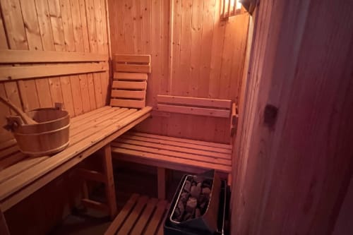 Traditional wooden sauna interior at Love Room hotel in Vannes with benches, bucket, and red lighting ambiance