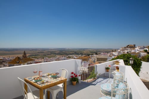 Terraza en la azotea con mesa de comedor con vistas a la blanca Medina Sidonia y el paisaje rural en Casa La Muralla