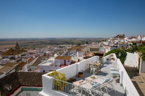 Terraza en la azotea de Casa La Muralla en Medina Sidonia con paredes blancas, mobiliario exterior y vistas panorámicas del campo