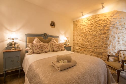 Dormitorio romántico en Casa La Muralla de Medina Sidonia con muros de piedra, ropa de cama elegante e iluminación cálida