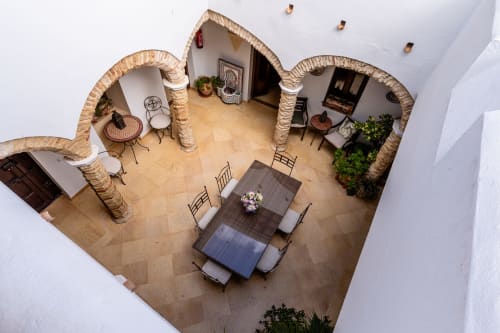 Vista aérea del patio andaluz de Casa de Medina con mesa de comedor, columnas arqueadas y suelos de azulejos en Medina