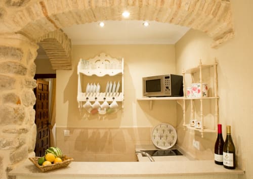 Pequeña cocina en estudio de Medina Sidonia con microondas, escurridor, botellas de vino y azulejos decorativos